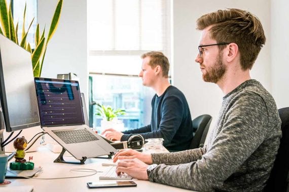 Stock photo of two digital workers in front of computer screens.